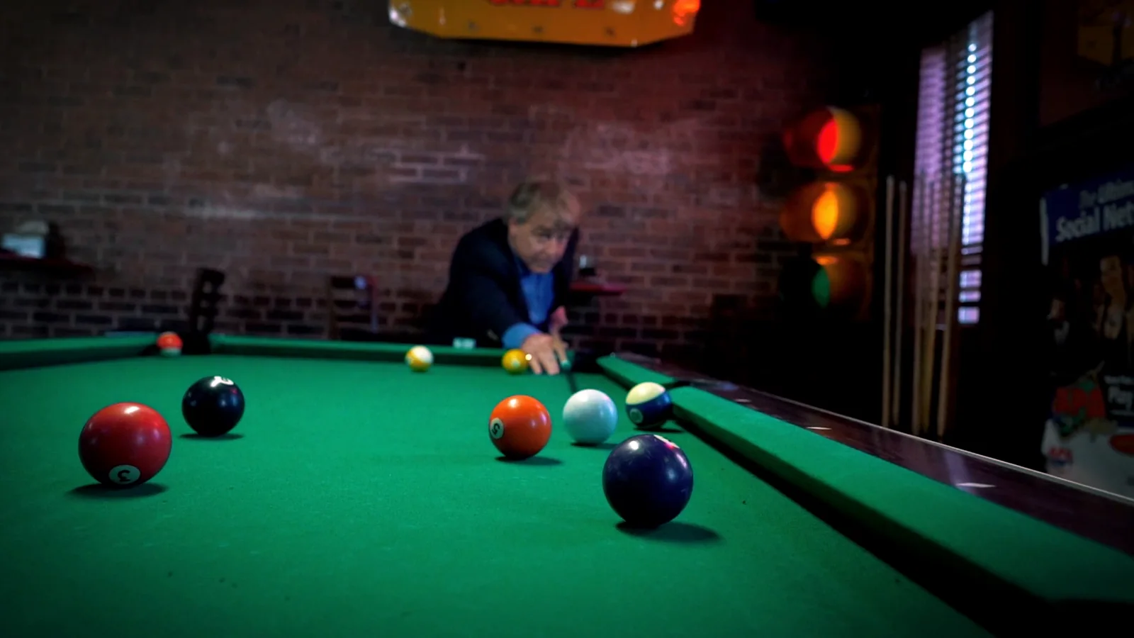 Greg Langford lining up a pool shot in a bar
