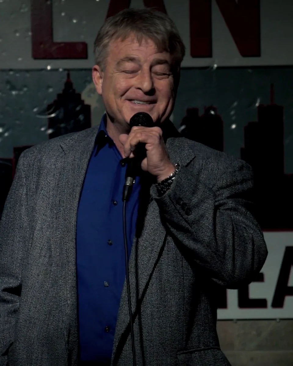 Greg Langford at the mic in front of the Atlanta Comedy Theater sign